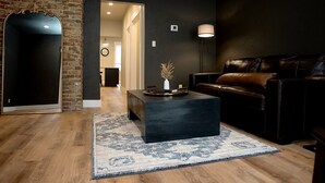 Una sala moderna con un sofá oscuro, una mesa de centro y una alfombra estampada.