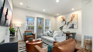 Un salon moderne comprenant un canapé, une table basse et un coin repas avec une table et des chaises.