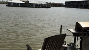 A boat with a grill and a gas cylinder, a wooden chair, and a view of buildings across the water. - The Pearl - Beautiful, renovated Houseboat in Venice Marina!  (Venice)