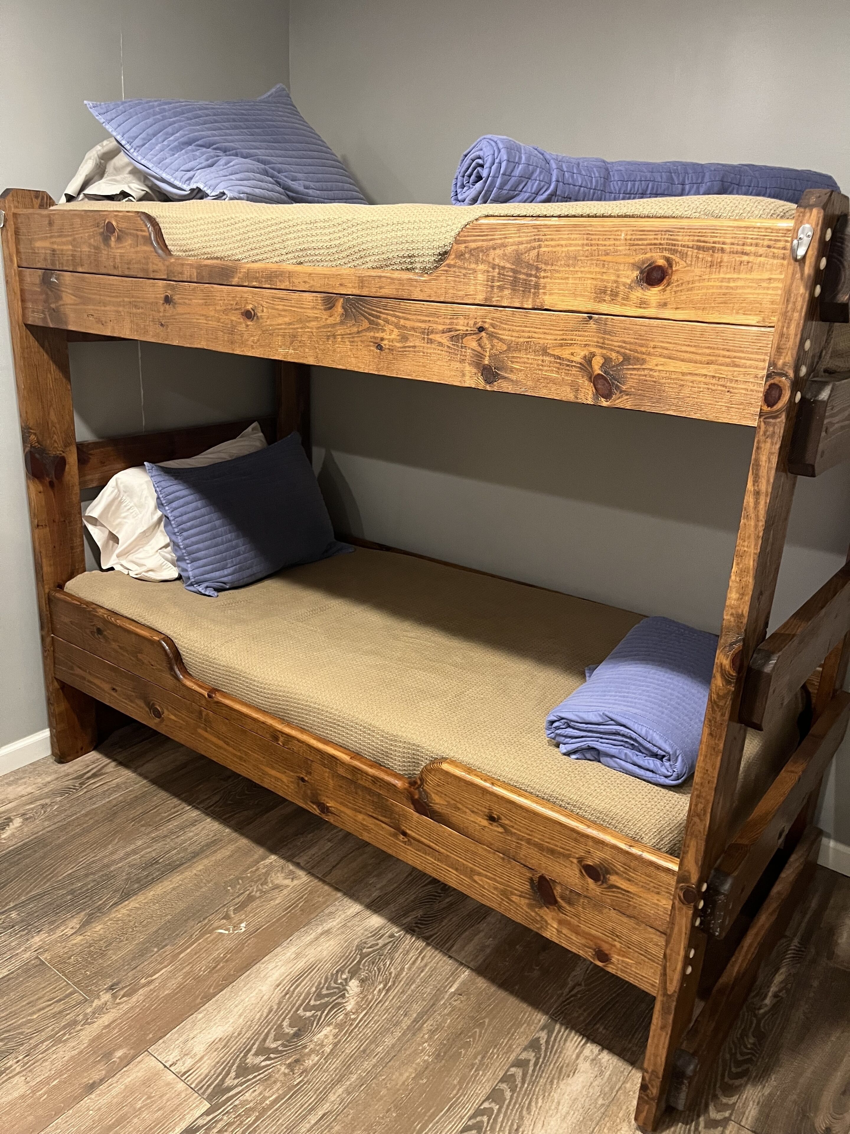 A bunk bed with a wooden frame, a mattress, and pillows.