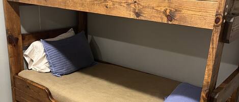 A bunk bed with a wooden frame, a mattress, and pillows.