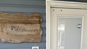 A wooden sign with the word "PEARL" on a wall, a closed door with a window, and a small white window below the door. - The Pearl - Beautiful, renovated Houseboat in Venice Marina!  (Venice)