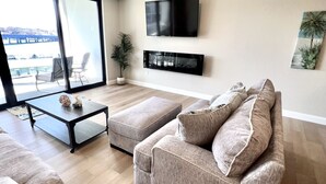 Una sala de estar moderna con un sofá grande, una mesa de centro y un televisor montado en la pared.