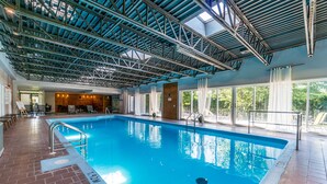 Ein Hallenbad mit hoher Decke und großen Fenstern.