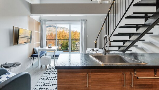 Eine moderne Küche mit schwarzem Arbeitsplatz, Spüle aus Edelstahl und einer Treppe mit einer weißen Bär-Dekoration.