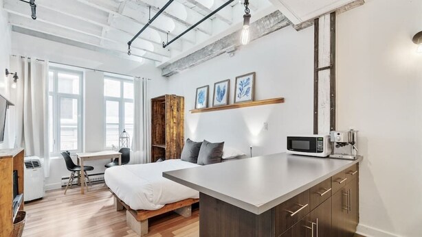 A modern hotel room with a bed, desk, and kitchenette. - INITIAL | MEMORY FACTORY | Centre-Ville de Québec (Québec City)