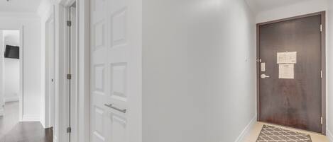 Un pasillo con puertas blancas, una puerta de madera oscura y un tapete estampado.