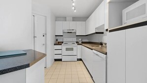 Une cuisine moderne avec des armoires blanches, un four encastré et un plan de travail.