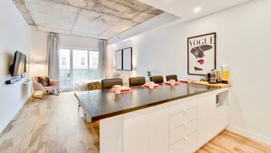 A modern kitchen with a central island, white cabinetry, and a concrete ceiling.