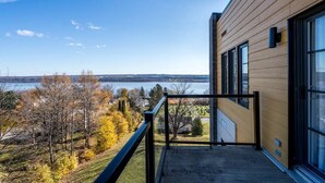 Een modern gebouw met een balkon met uitzicht op een meer en herfstkleurige bomen.