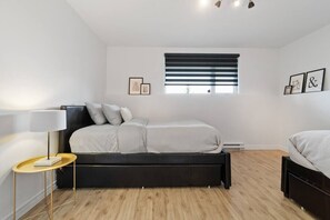 Une chambre à coucher moderne avec un lit, une table de chevet, une lampe et une fenêtre avec des stores.