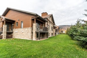 Une maison moderne à deux étages, dotée de fondations en pierre et d’un revêtement en bois, avec une véranda et une pelouse bien entretenue.