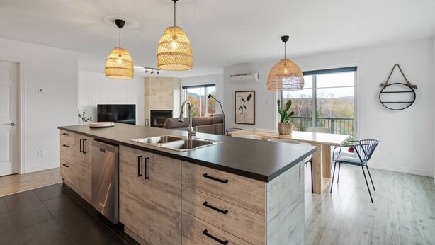 A modern kitchen with wooden cabinets, a large island, and pendant lighting.