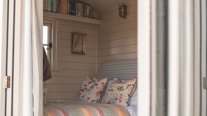 Une chambre confortable avec un lit, un petit pouf rond et une bibliothèque.
