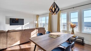 Ein modernes Wohnzimmer mit einem Holzesstisch, blauen Stühlen und einem beigen Sofa.