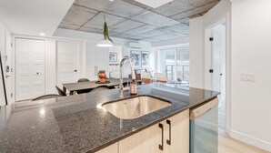 A modern kitchen with a granite countertop, stainless steel sink, and a dishwasher.