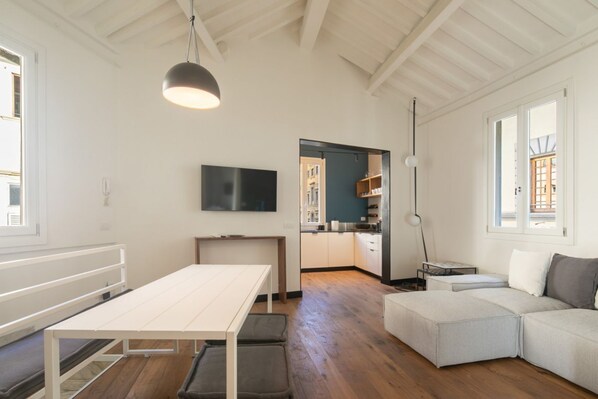 A modern interior with a dining table, sofa, and kitchen area.