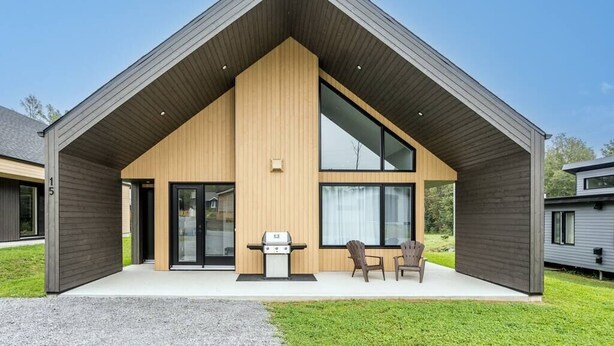 A modern house with a large porch, a grill, and two chairs. - Initial | Soeur No2 | MSA (Saint-Ferréol-les-Neiges)