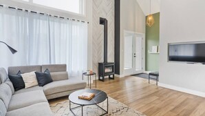 A modern living room with a sectional sofa, a round coffee table, a fireplace, and a flat-screen TV. - Initial | Soeur No2 | MSA (Saint-Ferréol-les-Neiges)