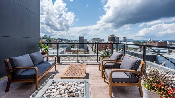 A rooftop terrace with a sofa, chairs, and a table with pebbles.