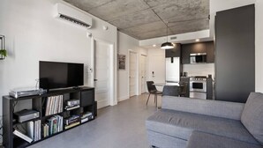 A modern living room with a grey sofa, a black entertainment unit, and a flat-screen TV.
