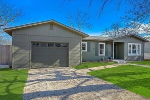 Une maison de plain-pied avec un garage, un porche à l’avant et une pelouse bien entretenue.