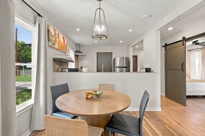 Una cocina moderna con una isla central, electrodomésticos de acero inoxidable y una zona de comedor con una mesa redonda y sillas.
