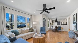Un salon moderne comprenant un canapé, des fauteuils, une table basse et un coin repas avec des chaises et une table.