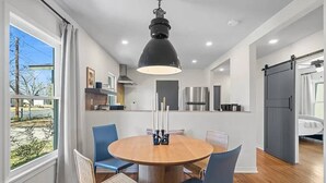 Une cuisine moderne dotée d’un îlot central, d’un coin repas avec une table ronde et d’une vue sur l’extérieur.