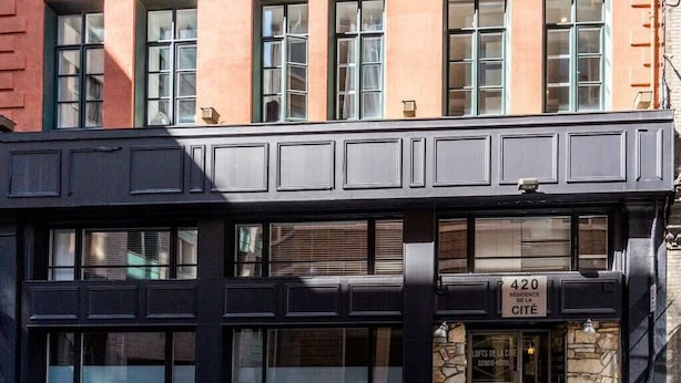A building with a black facade, multiple windows, and a sign indicating it is a residence of the city.