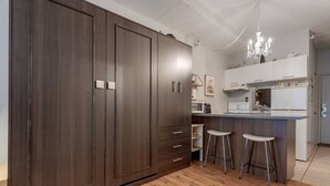 A modern kitchen with dark wood cabinets, a central island with stools, and a chandelier.