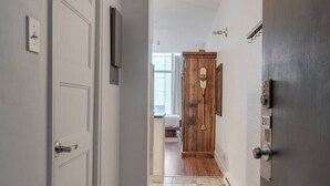 A hallway with a wooden door, a white door, and a number plate '200'.