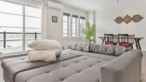 Een moderne slaapkamer met een groot bed, een eettafel met stoelen en uitzicht op een besneeuwd landschap door grote ramen.