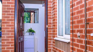 Une étroite entrée mène à un bâtiment en briques, avec une porte et une fenêtre sur le côté droit.