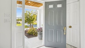 A white door with a grey panel, a potted plant, and a view of a garden and a lake. - Minutes from Downtown St. Michaels | Pool | Hot Tub | Pickle Ball Court (Saint Michaels)