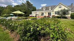 A large house with a covered porch, a swimming pool, and lush greenery. - Minutes from Downtown Easton and St. Michaels | Pool | 1st Floor Bedroom | Pet F (Easton)