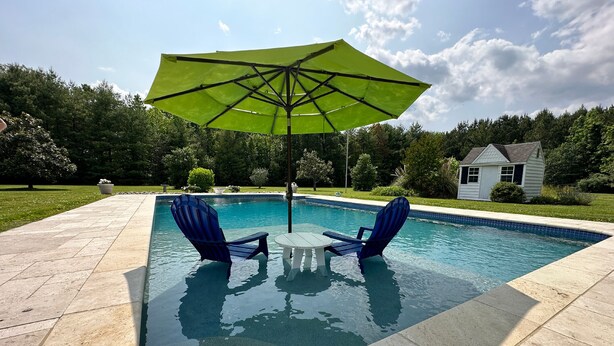 A swimming pool with two blue chairs and a green umbrella. - Minutes from Downtown Easton and St. Michaels | Pool | 1st Floor Bedroom | Pet F (Easton)