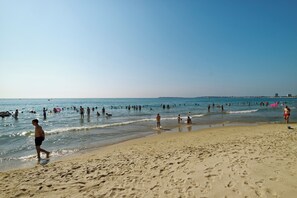 A beach with people swimming and walking on the sand.
