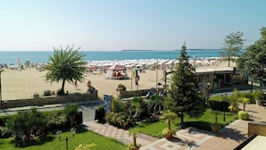 Een hotel aan het strand met uitzicht op zee, terras en een overdekt gedeelte.