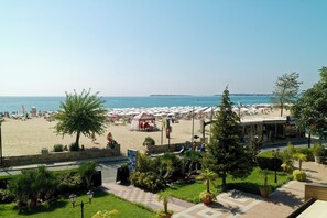 A beachside hotel with a view of the sea, outdoor seating, and a covered area.