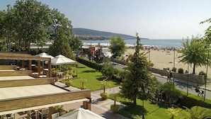 Een restaurant aan het strand met terras, uitzicht op het strand en een heldere lucht.