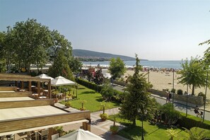 A beachside restaurant with outdoor seating, a view of the beach, and a clear sky.