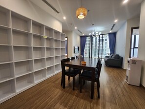 A modern living room with a dining table, chairs, a sofa, and a large window with curtains. - Vinhomes Skylake next to Keangnam  (Hanoi)