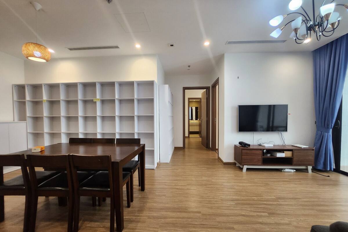 Ein modernes Wohnzimmer mit Essbereich, Holzboden, Flachbildfernseher und einer eingebauten Bücherreol.