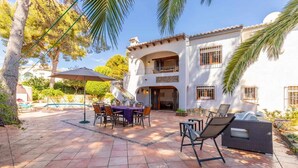 A patio with a table and chairs, a pool, and a two-story building with balconies. - VILLA FELIZ, beach, pool, wifi, a/a, 10 pax (Moravit)