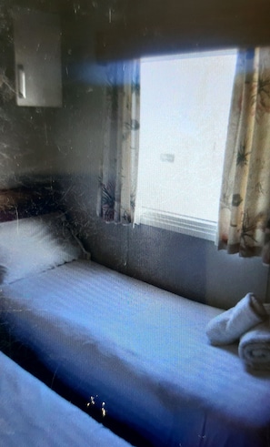 Ein Zimmer mit einem Bett, einem Vorhangfenster und einer Wandleuchte.