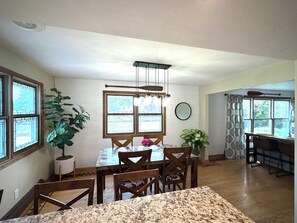 A dining area with a wooden table, chairs, and a hanging light fixture.