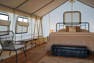 Una habitación con tienda, una cama, una silla, un banco y una mesa.