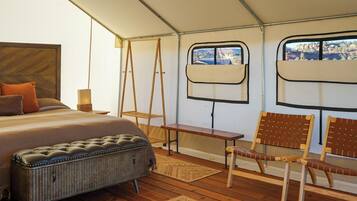 Een tentkamer met een bed, een bank, stoelen, een raam met uitzicht en een kleine tafel.