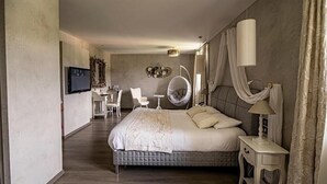 A modern hotel room with a large bed, a TV, a desk, and a hanging chair. - Chateau De La Falque (Saint-Geniez-d'Olt-et-d'Aubrac)